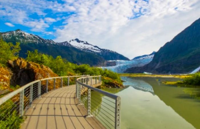 A wooden pathway along Juneau's coastline, framed by mountains and glaciers in the distance