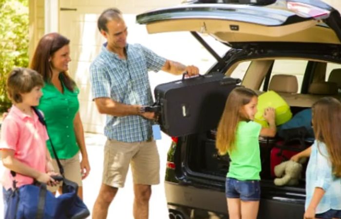 a family of five loading their suitcases into a black minivan as they prepare for their cruise to Hawaii