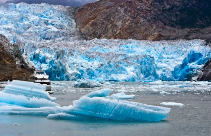 a small ship navigating past glaciers that have broken off from Tracy Arm Fjord in Alaska