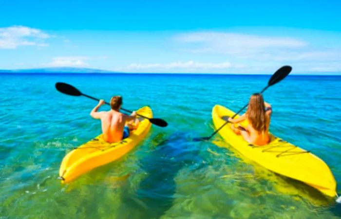 a man and a woman in yellow kayaks paddling off the coast of Hilo, Hawaii