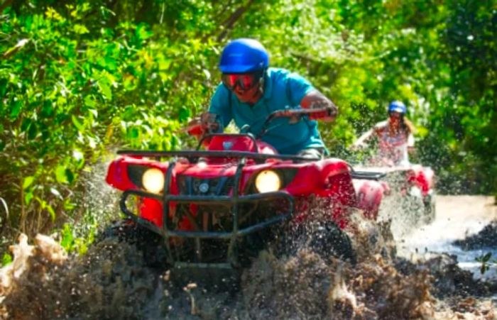 A man enjoying himself as he drives an ATV through muddy waters in Costa Maya.