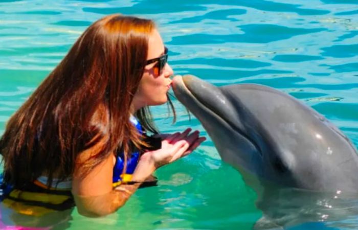 A woman sharing a kiss with a dolphin during an excursion in Costa Maya.