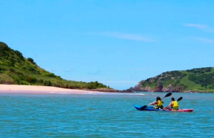 a man and woman paddling in blue and red kayaks off the coast of Mazatlan