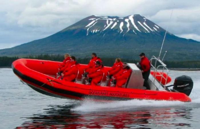 a group of seven adventurers exploring the volcanic coast aboard an orange ocean raft