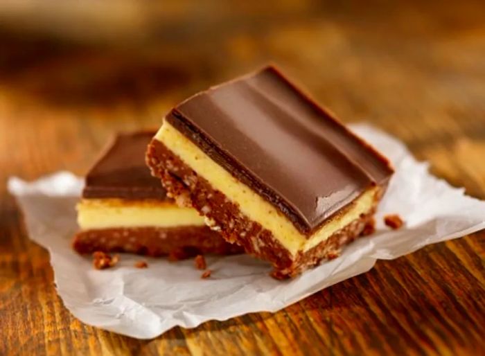 Nanaimo Bars consist of a layer of yellow custard nestled between crunchy crackers and a rich chocolate topping.