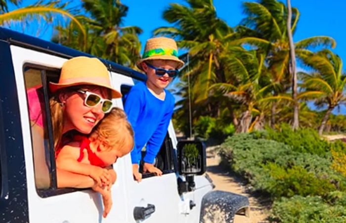 Siblings gazing out the window of a jeep during a safari adventure in Aruba.