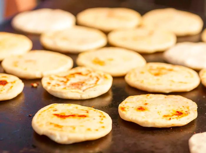 pupusas sizzling on a griddle grill in Mahogany Bay