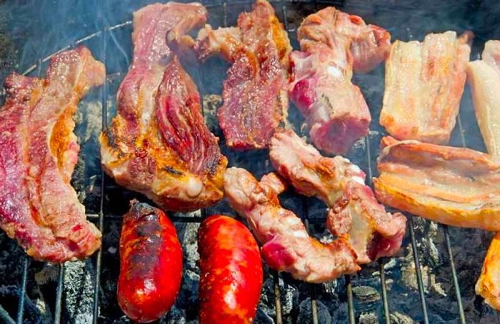 steak, pork, and chorizo sizzling on a grill in Mahogany Bay