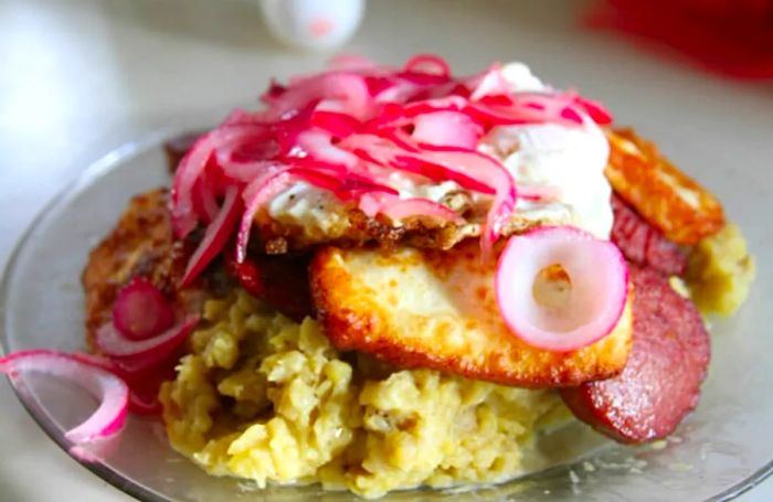 Mangú served alongside eggs, sausage, and onions