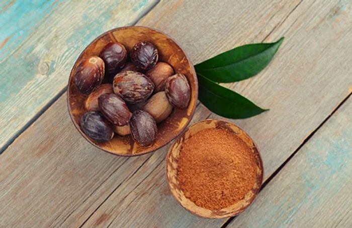 a bowl filled with whole nutmegs in their shells alongside ground spice