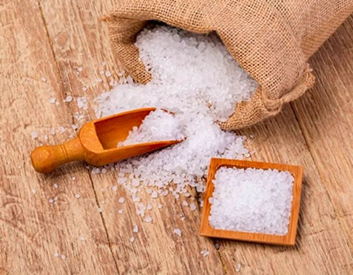 a bag of sea salt resting on a wooden scoop and plate