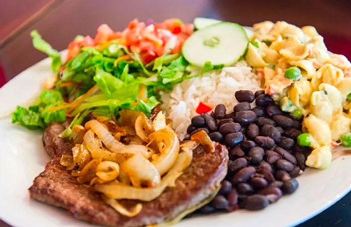 A serving of casado from Limon, featuring rice, black beans, pork, and salad