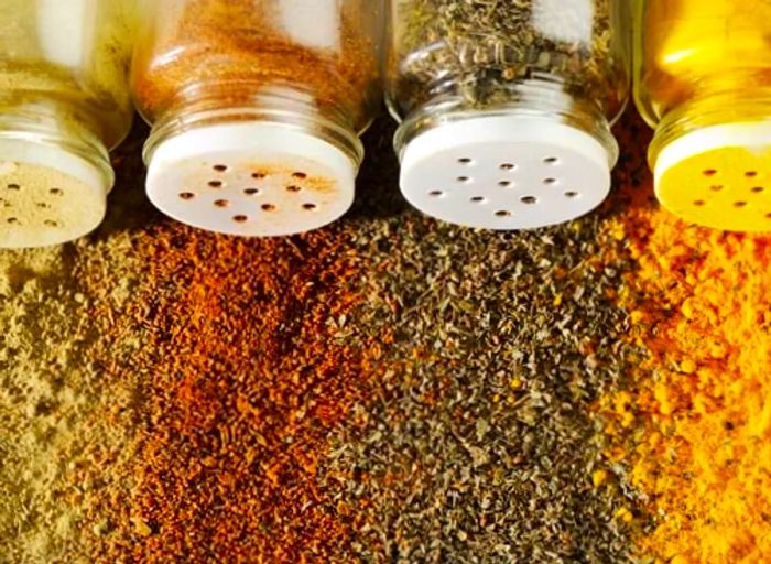 Four glass bottles containing different spices spilled across a table