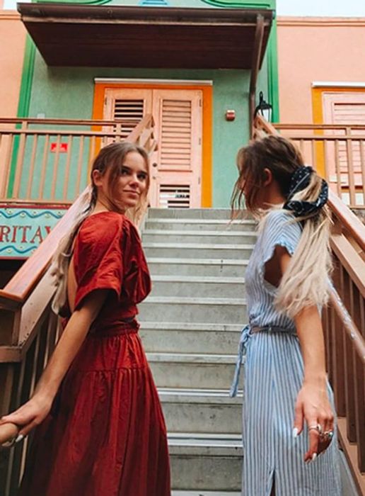 Tess & Sarah pose on the staircase beside a colorful building