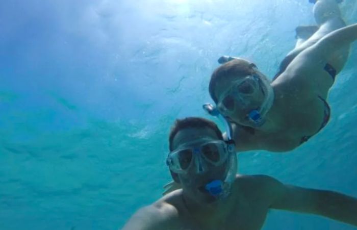 A man and woman capturing a selfie while snorkeling in Hawaii