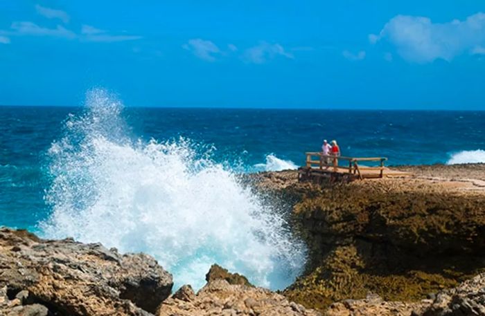 tourist observing waves crashing against rock formations at Shete Boka National Park