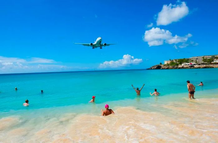 Beachgoers at Maho Beach gather to watch a commercial airplane fly overhead as it prepares to land