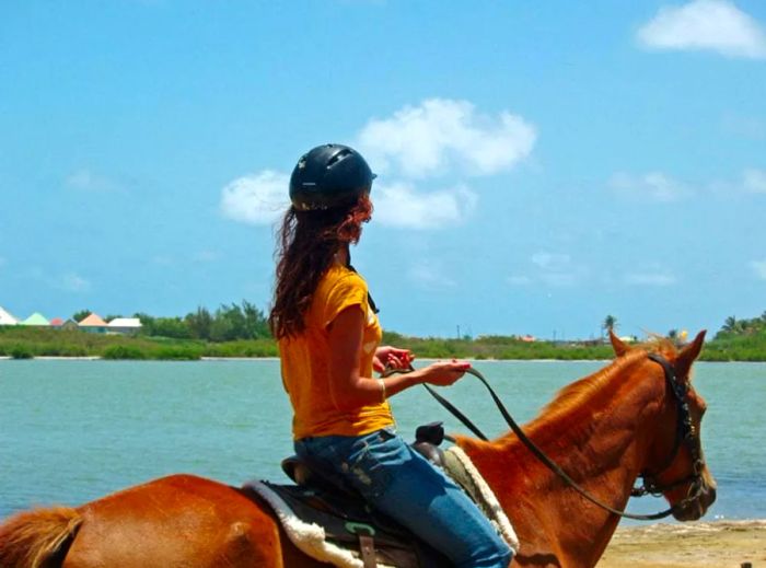 A woman rides horseback along the stunning coast of St. Maarten