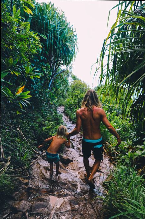 father and son trekking on a muddy jungle path