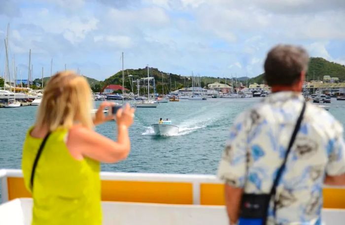 A couple captures a photo of the St. Maarten coastline during a boat tour as another vessel passes by