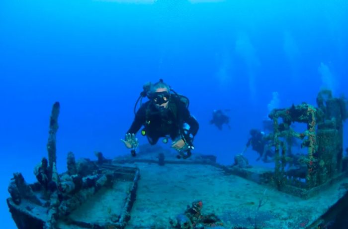 A man waves while scuba diving above a shipwreck in St. Maarten