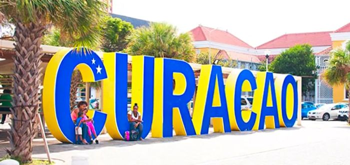 A vibrant blue and yellow Curacao sign framed by palm trees