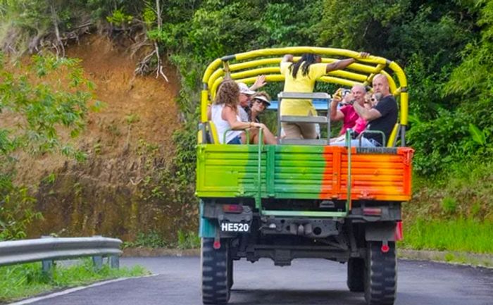 A small group waves and snaps photos while riding on the back of an old military jeep en route to Roseau