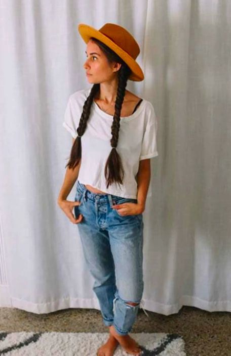 Drea glancing to the side, sporting fishtail pigtails and a brown hat