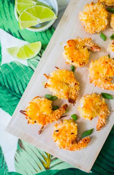 Coconut shrimp on a kitchen counter with dipping sauces and lime wedges