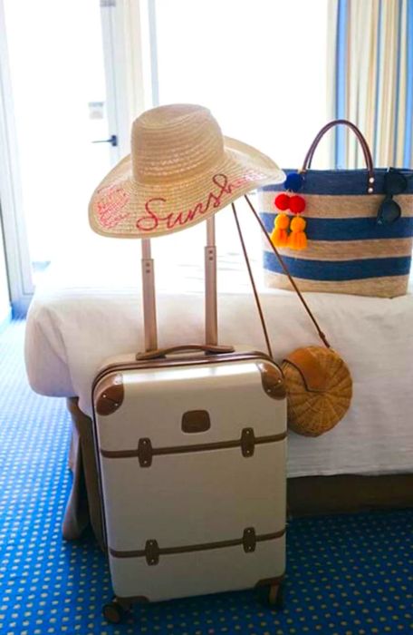 A suitcase, beach bag, and sun hat arranged in a balcony stateroom on the Dinogo Victory