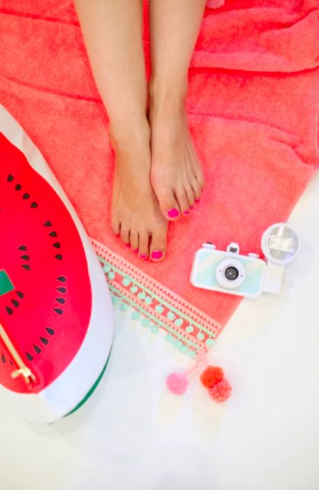 Feet and a camera resting atop the DIY pompom beach towel