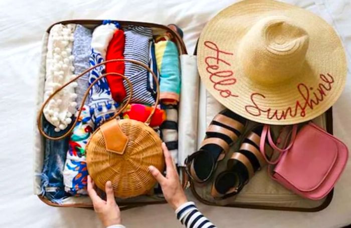 Aerial shot of a packed suitcase with hands reaching inside