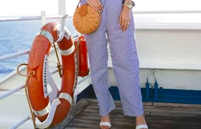 Caroline in blue and white striped trousers, holding a basket bag