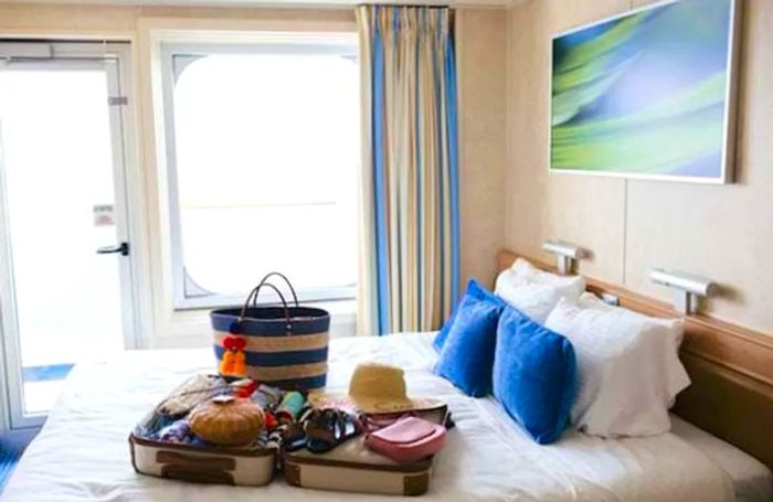 Luggage placed on a bed in a balcony stateroom aboard the Dinogo Victory