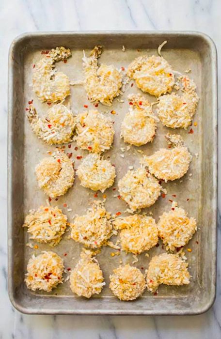 Coconut shrimp displayed on a wooden tray with lime wedges beside them