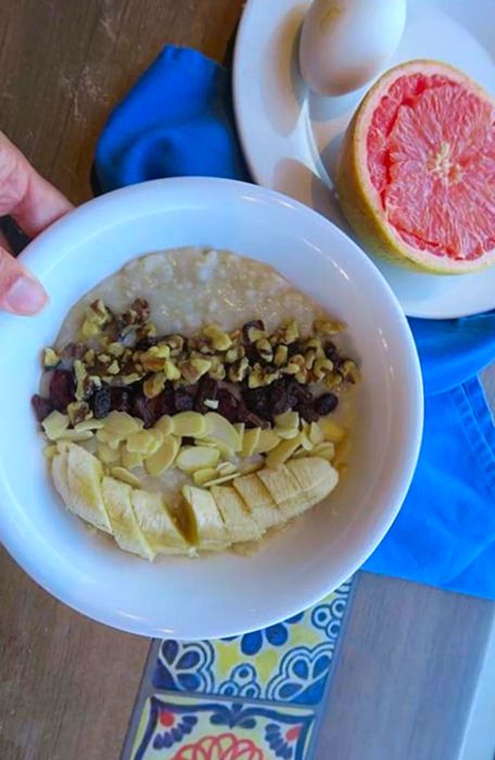 Oatmeal loaded with banana, walnuts, almonds, and raisins, served with an egg and half a grapefruit on the side