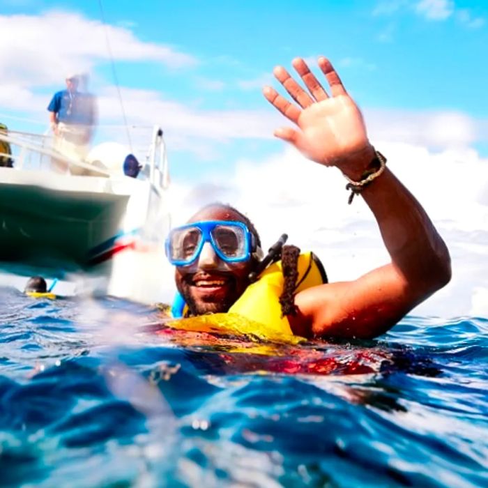 a man snorkeling in the Caribbean Sea, waving at the camera