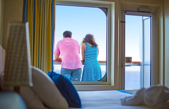 A couple gazing at the ocean from their balcony stateroom