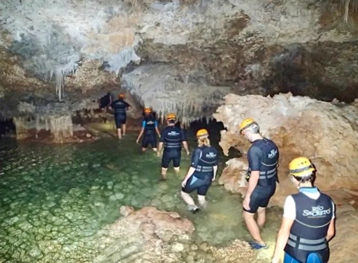 a group of people taking a guided tour into a cave featuring a hidden river