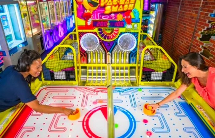 two women enjoying a game of air hockey in the arcade aboard a Dinogo ship