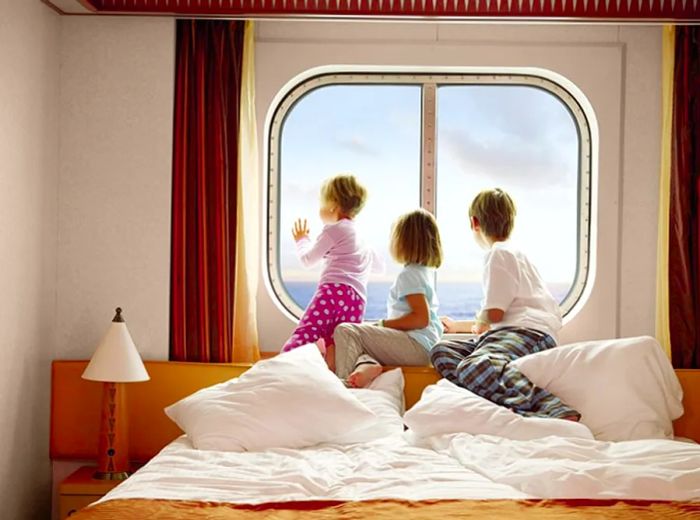 Three children peering out the window of their stateroom