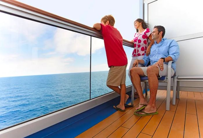 Parents enjoying the view from their cruise balcony with their son, gazing out at the ocean