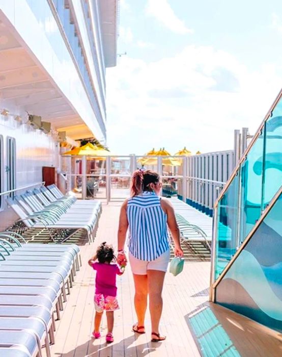 A mother and daughter strolling hand in hand along the cruise deck