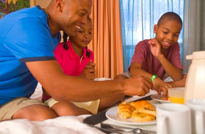 A dad enjoying breakfast in the stateroom with his son and daughter