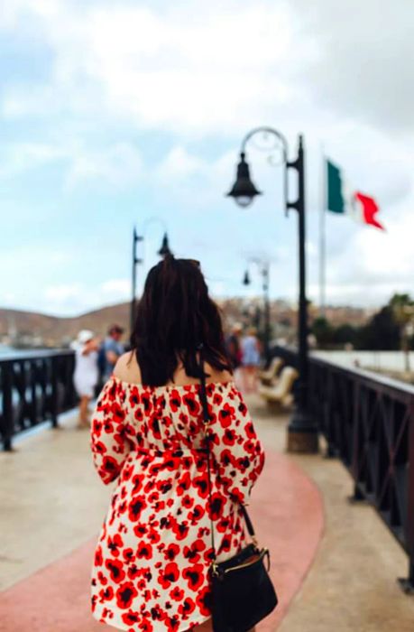 woman in a red and white dress enjoying the scenery as the Mexican flag flutters in the background