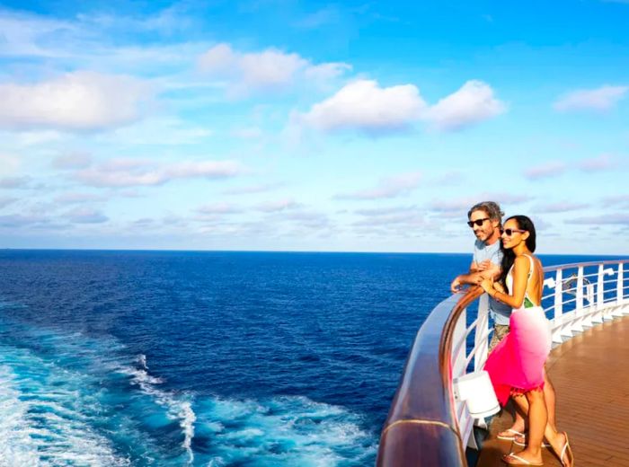 couple gazing over the deck railing at the sea