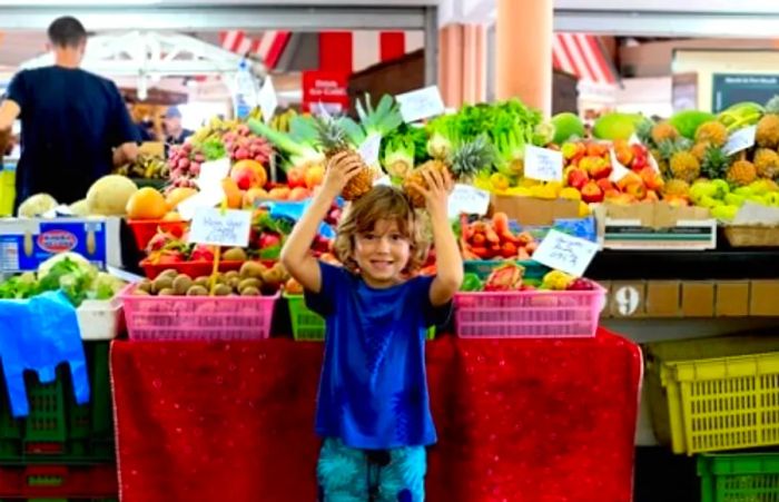 a child playing with pineapples at a marketplace in Noumea