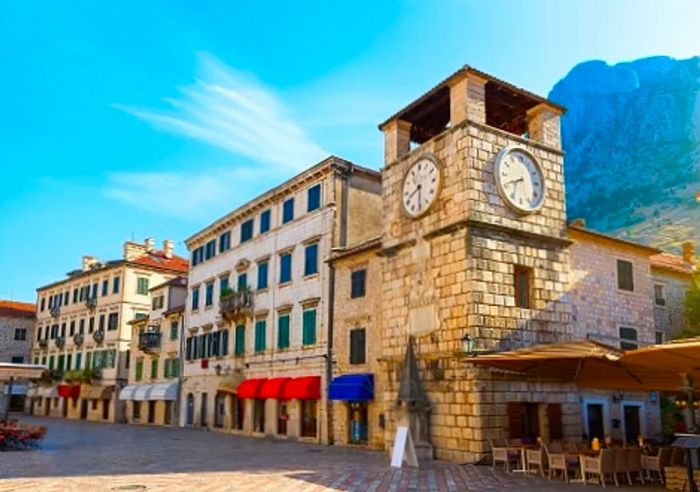 A towering clock and various shops in Kotor's old town