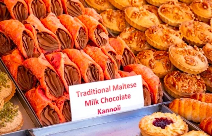 a selection of traditional Maltese milk chocolate kannolis and various treats displayed in a bakery in Malta