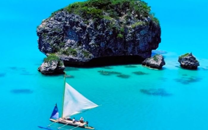 a boat gliding past a towering rock in Upi Bay